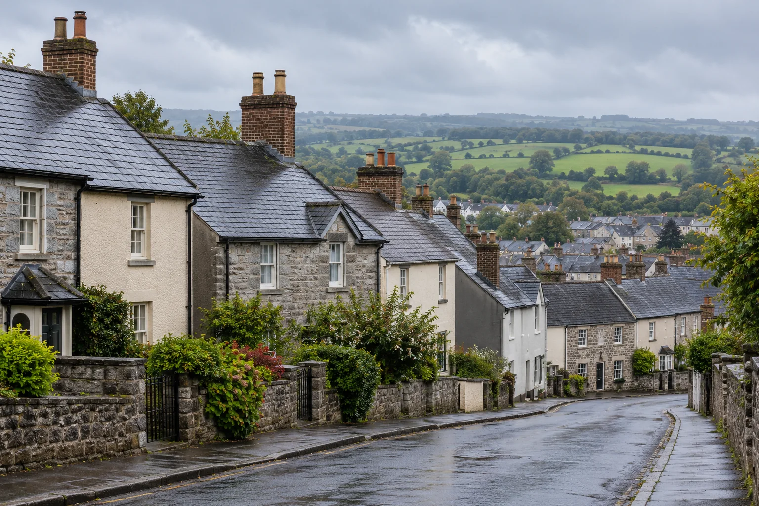 Stone-fronted and rendered town homes with dark slate roofs, brick chimneys and farmland beyond.